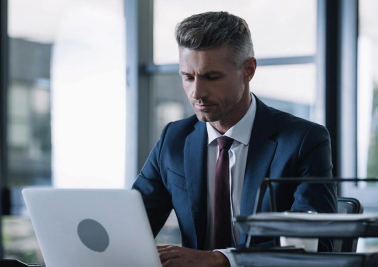 Homme en costume devant son ordinateur